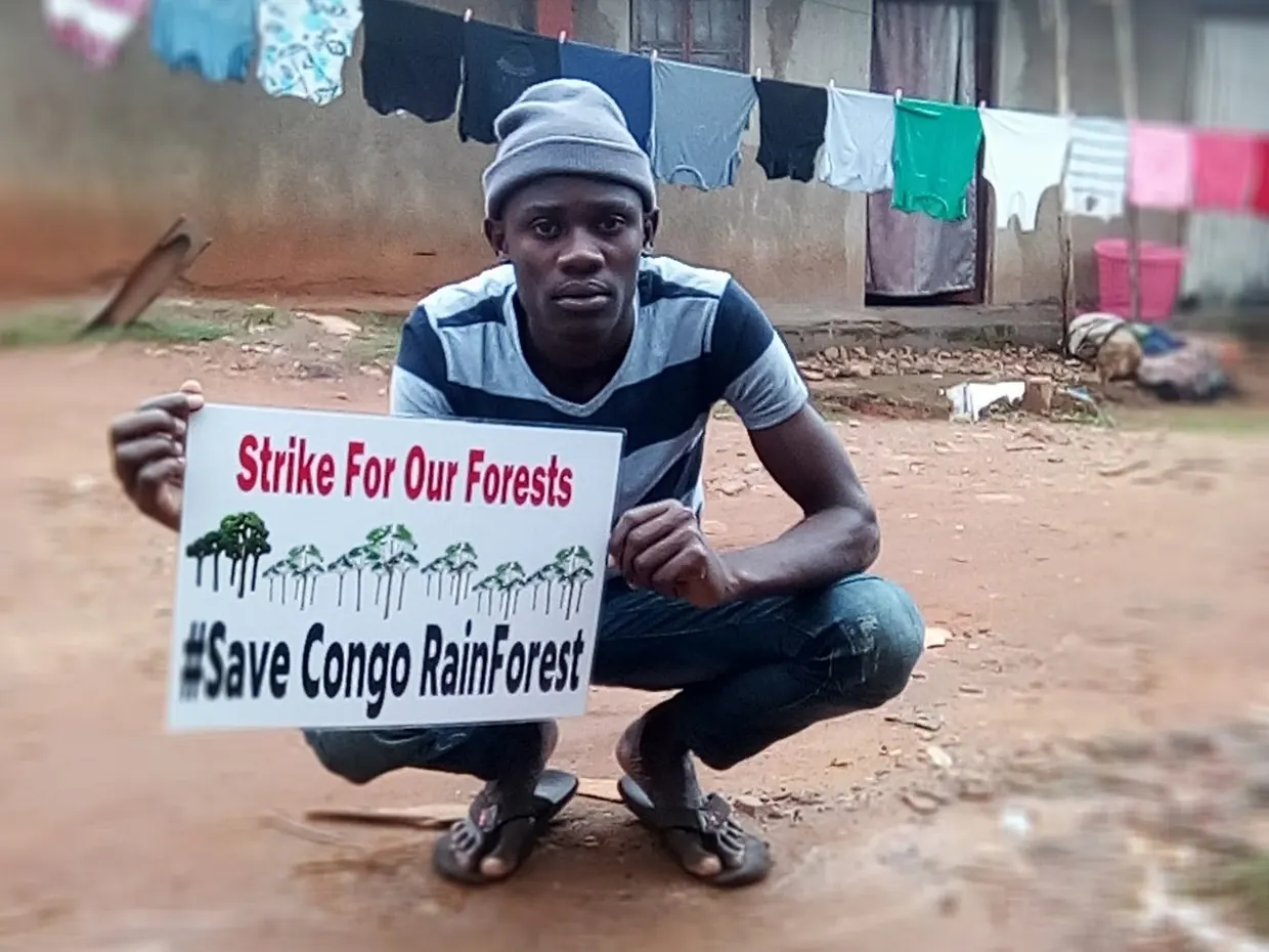 A young activist holding a Save Congo Rainforest sign