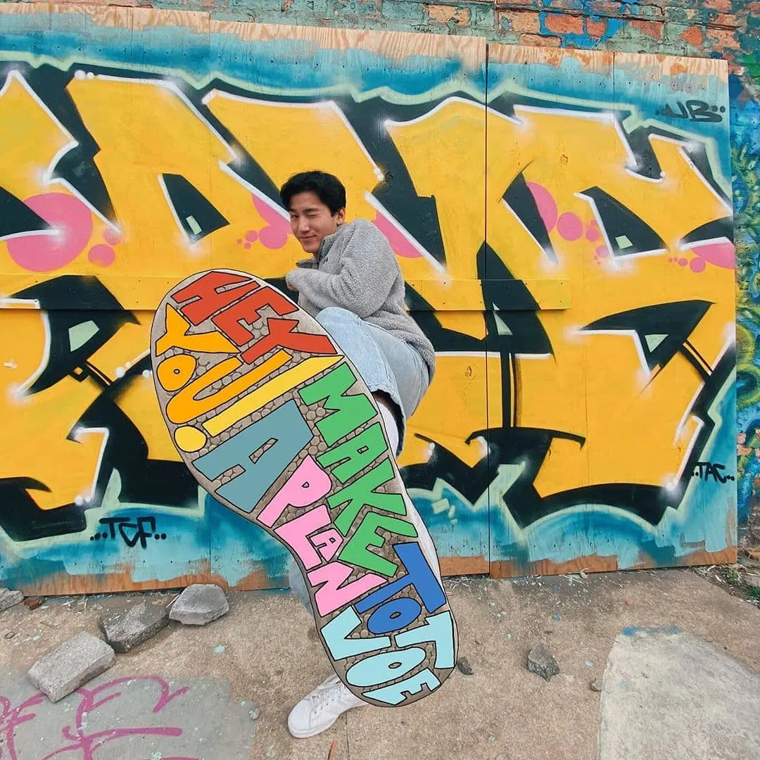 A young organizer in front of a colorful mural